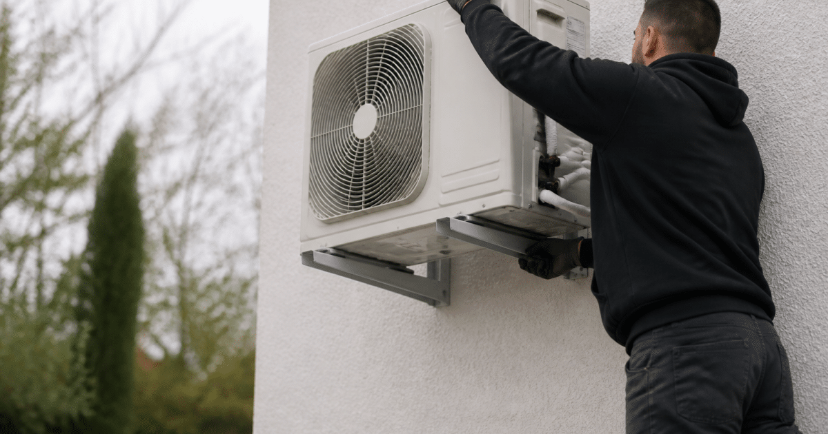 Personne installant unite exterieure pompe chaleur sur mur